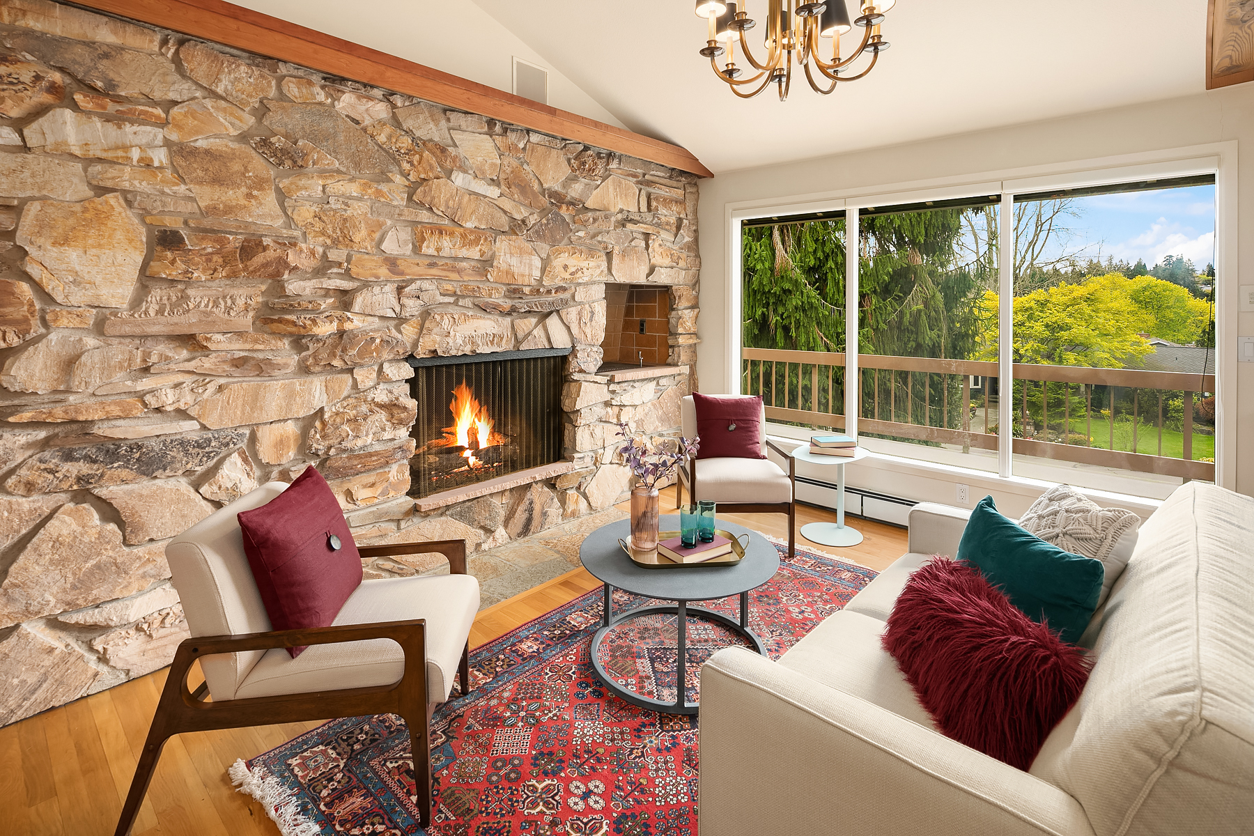 staged midcentury living area with exposed stone fireplace and burgundy and teal accents