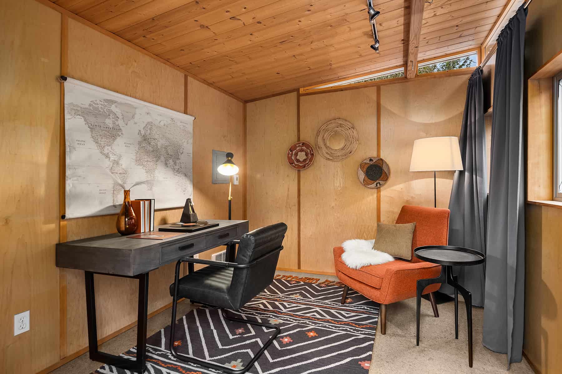 outdoor den staged as a home midcentury style home office with gray and orange accents and a map on the wall